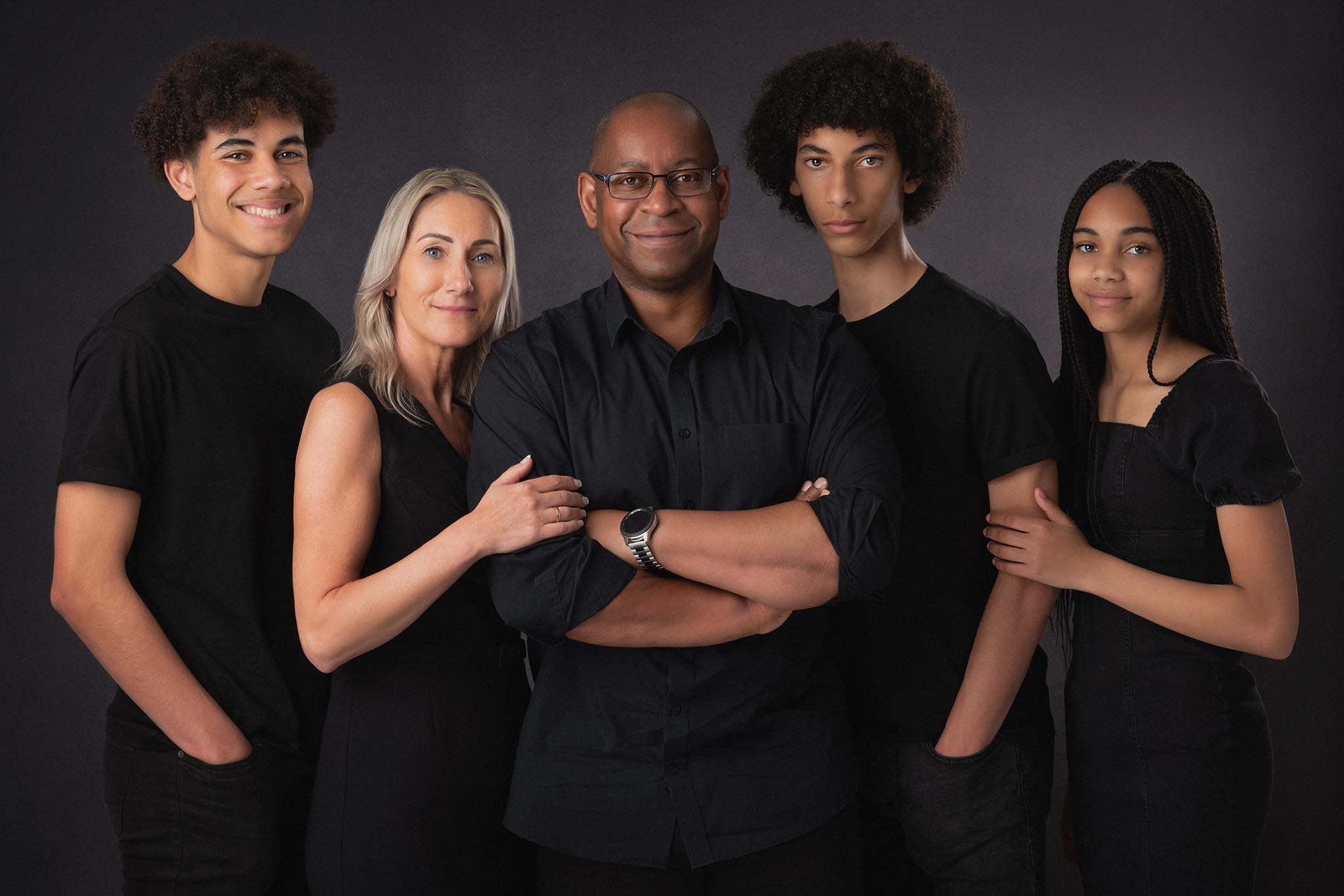 Family with teenagers photogrphed in black clothes on dark backfround by Family Photographer Preston Lancashire