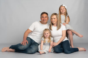 family with two young girls in white t-shirts on white background photo studio by Family photographer in preston lancashire
