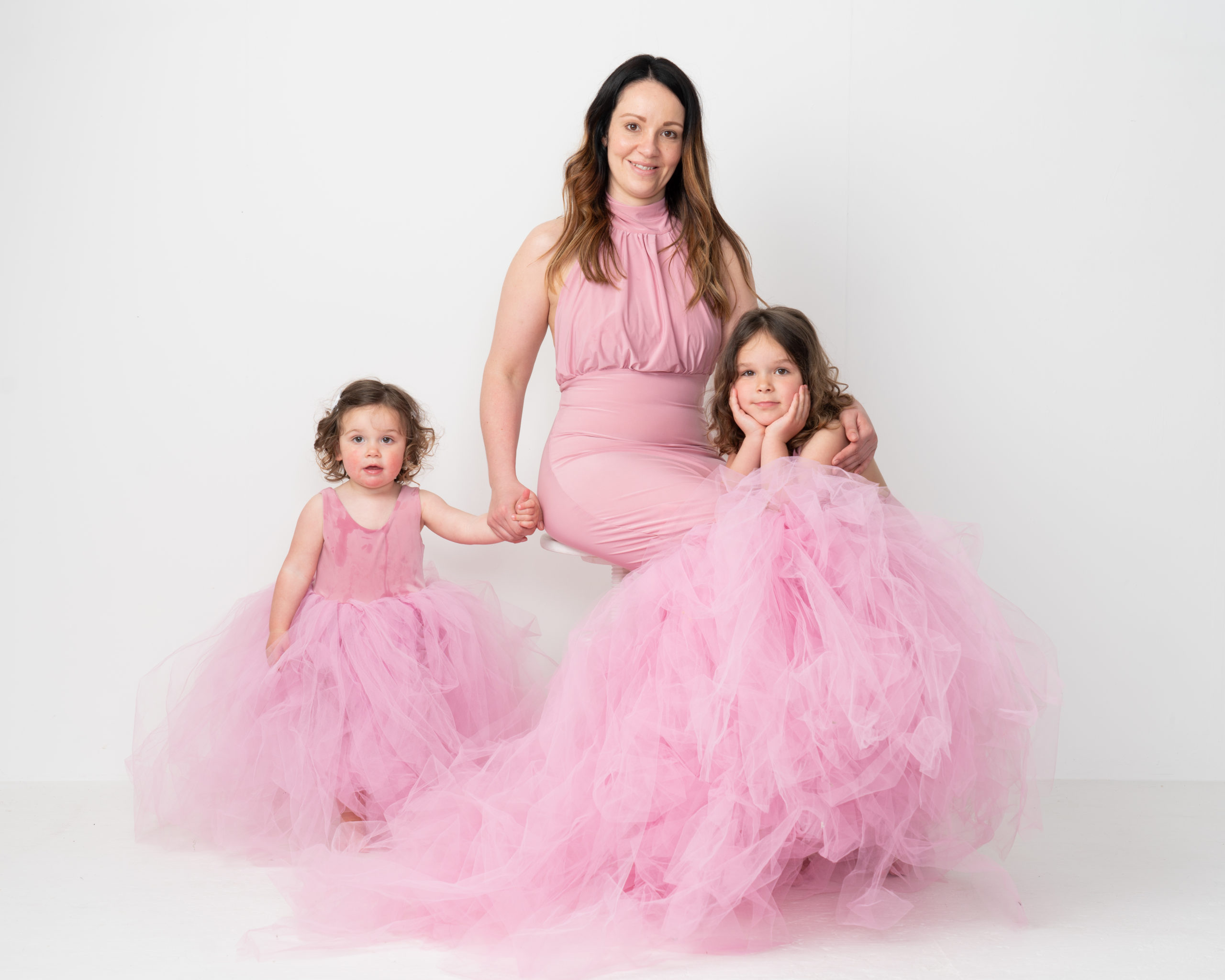 mum and daughters in pink dresses in light photography studio by Family photographer in preston lancashire