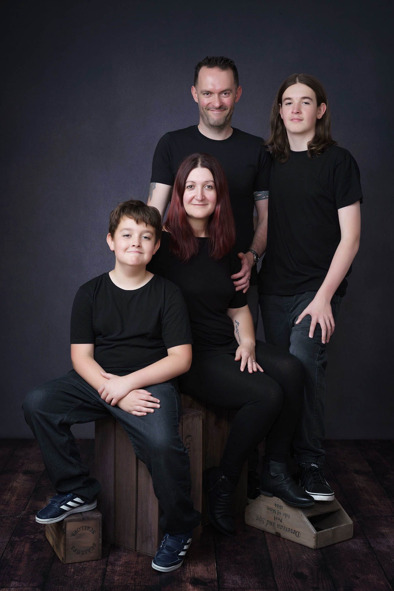 family in black on dark backround by Family photographer Lancashire