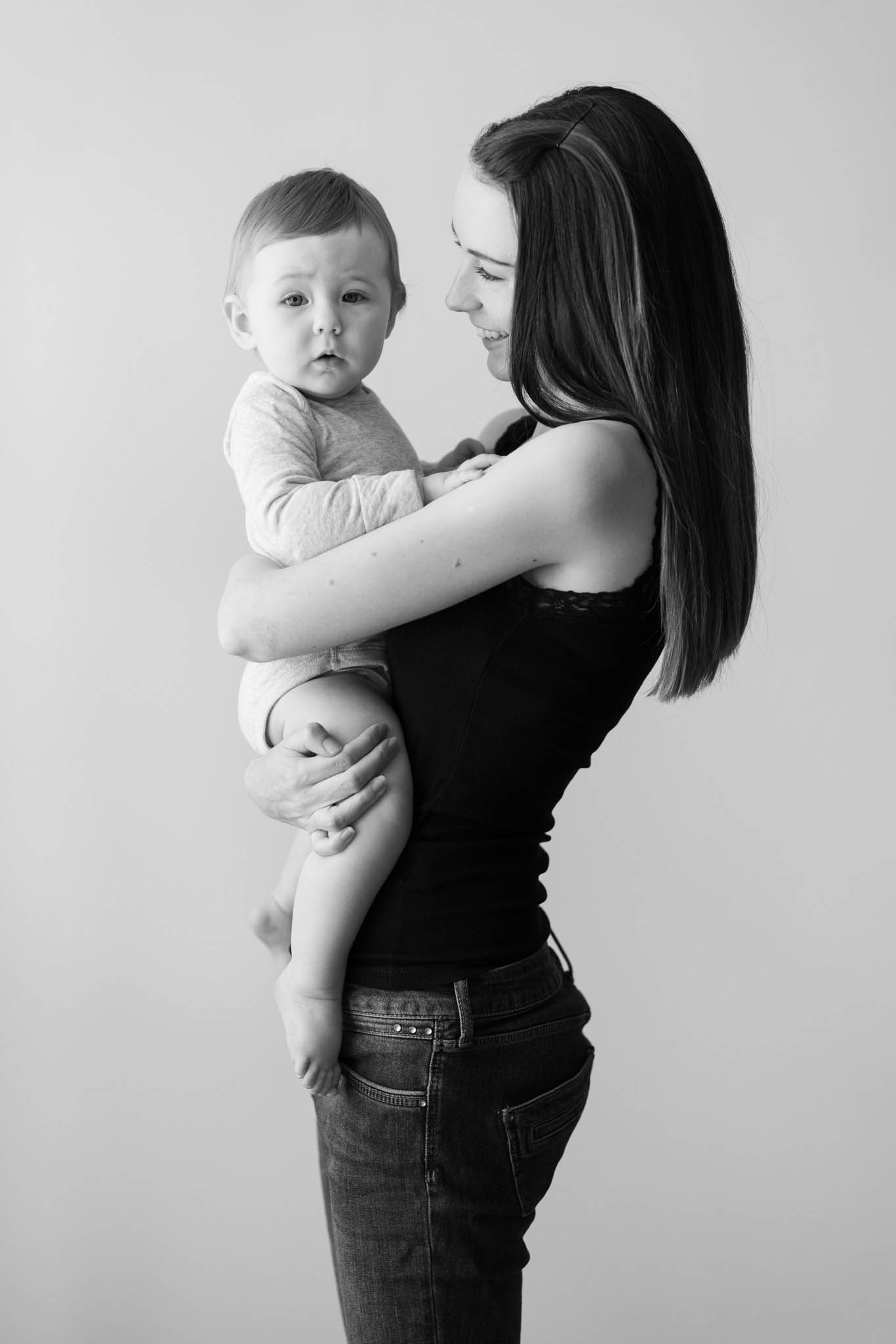 black and white portrait of mum wearing black with baby girl in her arms by Family photographer Lancashire